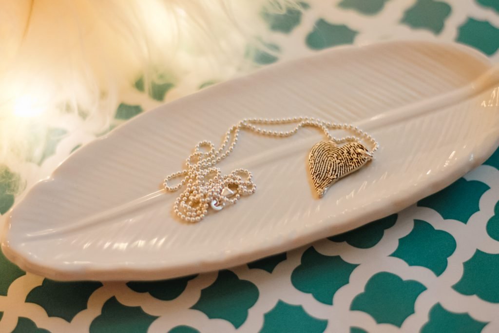 Flatlay of Smallprint tendertouch necklace on glass feather tray