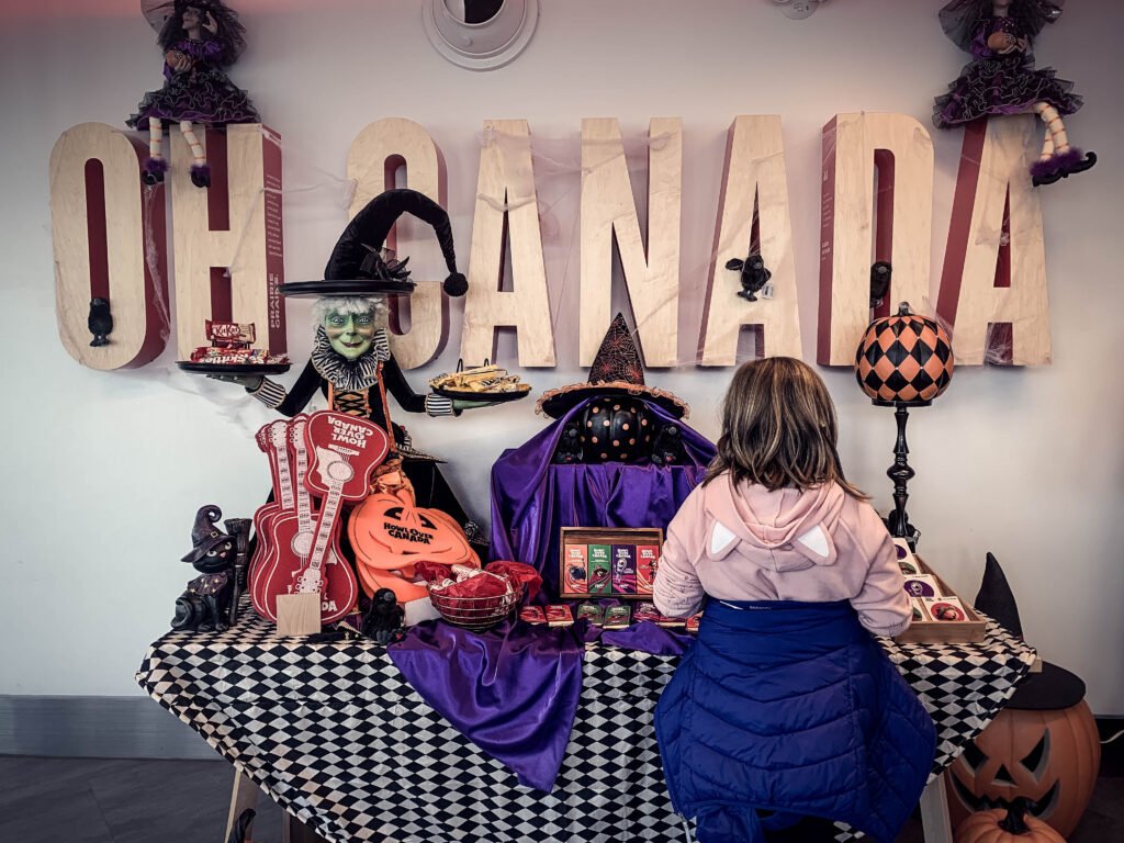 Girl standing in front of HowlOver Canada souvenir table with Oh Canada sign