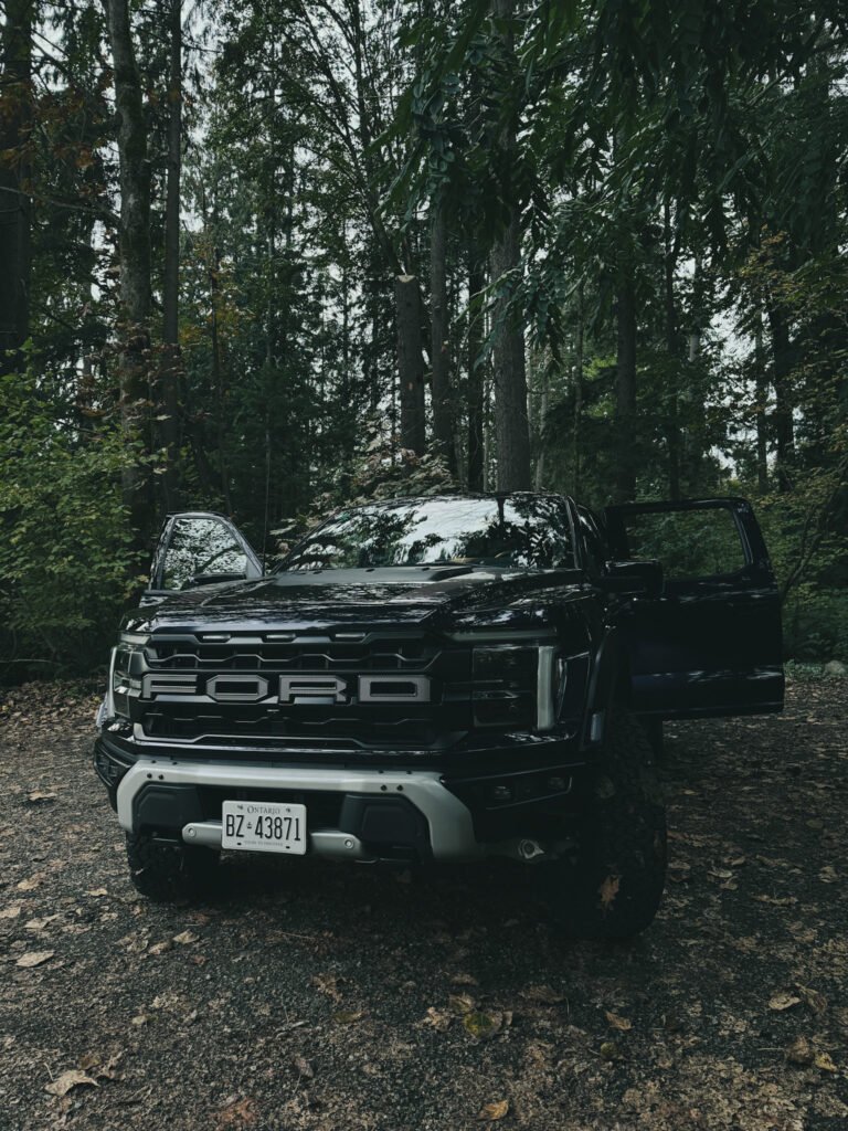 Ford F-150 Raptor parked in woods with doors open