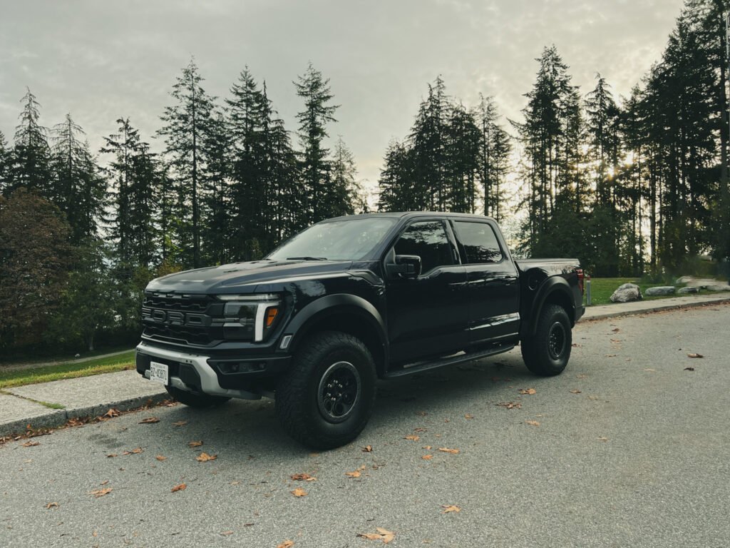 Ford F-150 Raptor parked on side of the road with trees in background